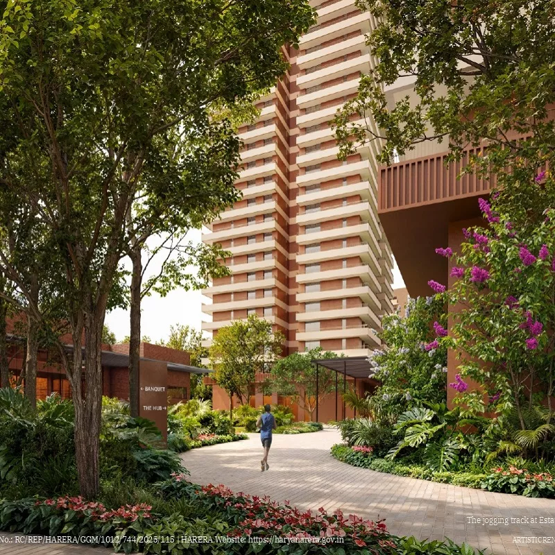Modern high-rise residential tower with landscaped jogging track, lush greenery, and garden pathway in a premium housing society.